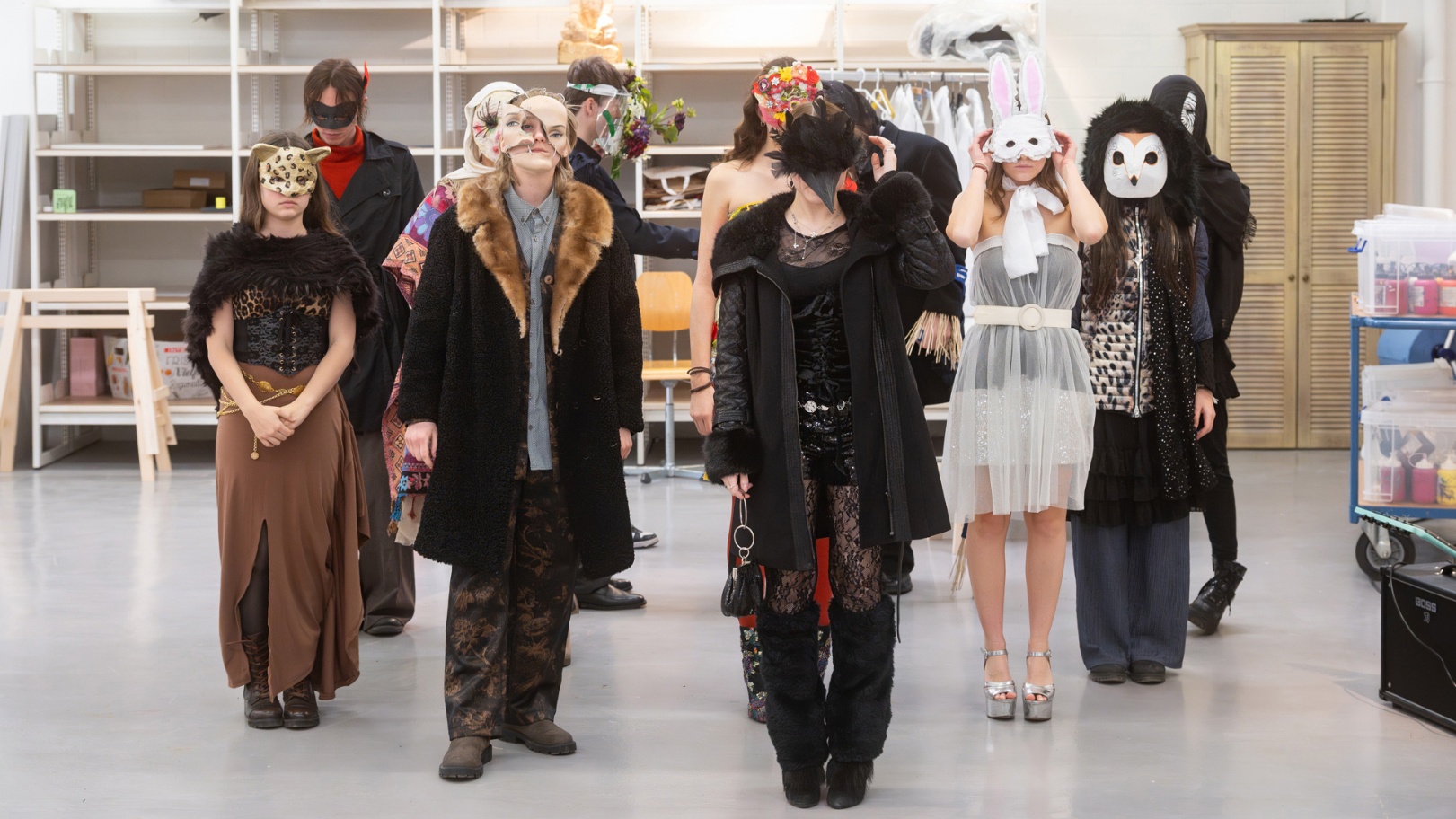 Gruppe von Schülern in selbst gestalteten Kostümen und Masken im Atelierraum der Kunstschule.